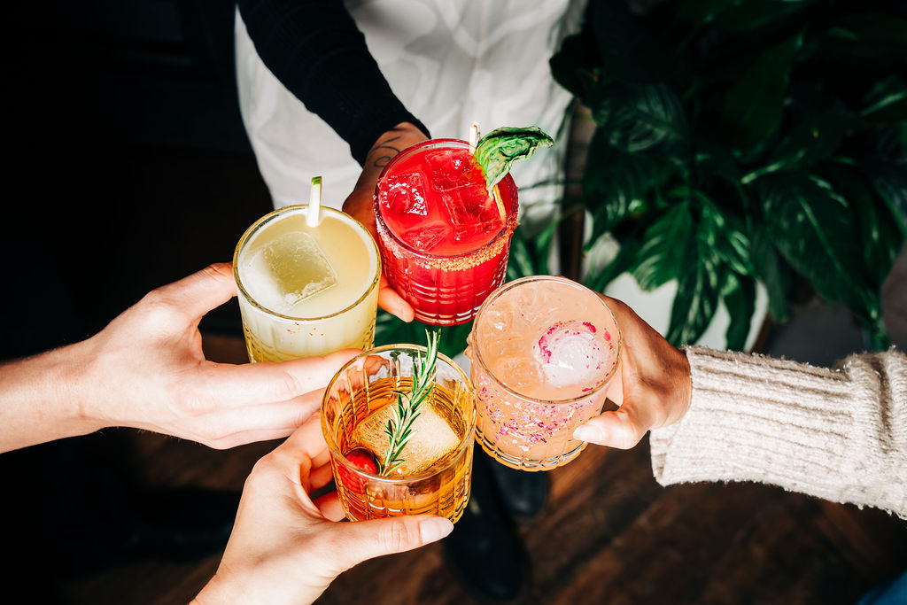 Cocktail cheers toast at a Stone House Nevada City private event — guests raise craft cocktails over a family-style table