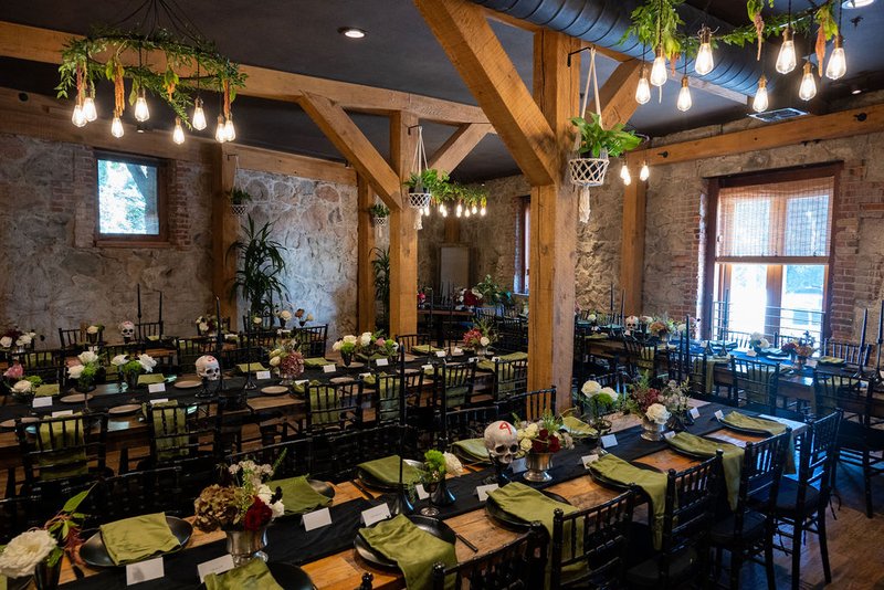 The Great Hall reception space at Stone House Nevada City — original 1857 stone walls, vaulted ceilings, long banquet tables set for a wedding dinner