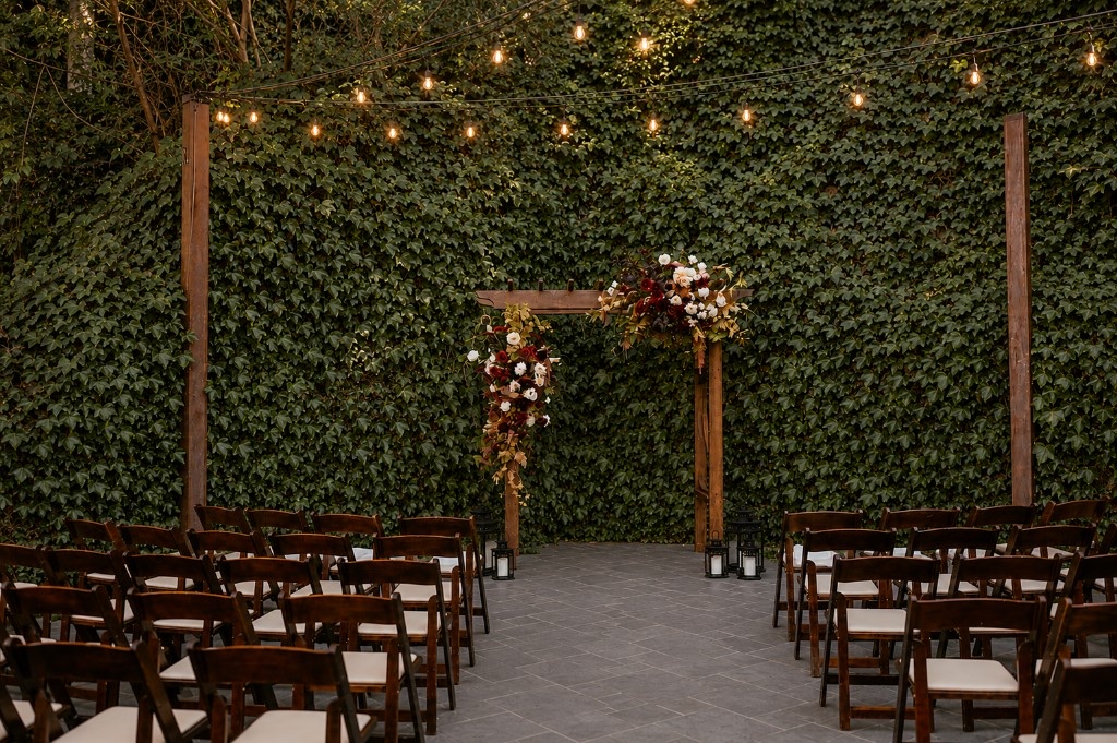 Outdoor wedding ceremony in The Courtyard at Stone House Nevada City with ivy wall and floral arch